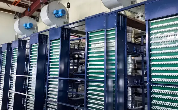 Deretan alat pengumpul telur kandang tipe H dengan kipas ventilasi di atasnya
